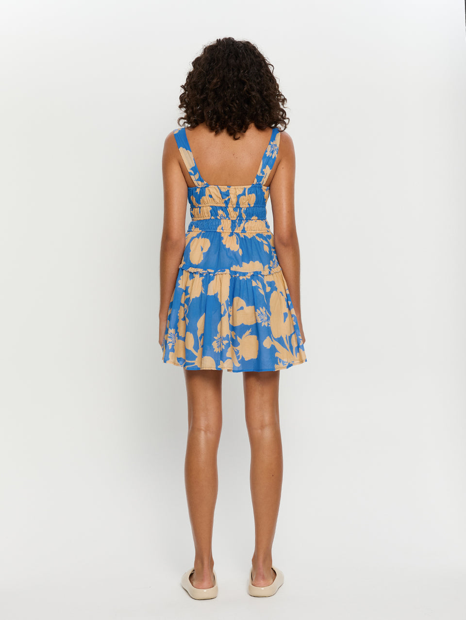Aurora Mini Gathered Dress KIVARI | Model wears blue floral mini dress back view