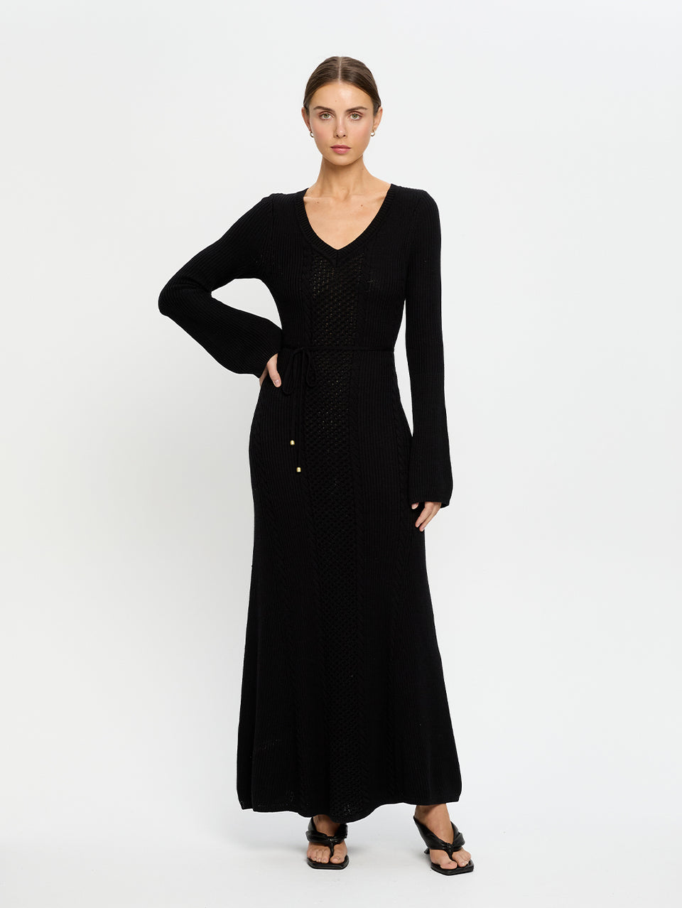 Woman wearing a black dress with long sleeves on a white background