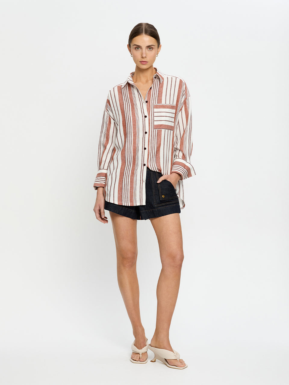 Woman wearing a striped shirt and black shorts on a white background