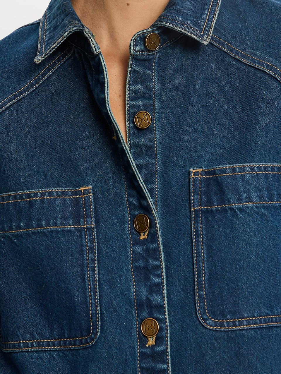 Close-up of a blue denim jacket with buttons and pockets.