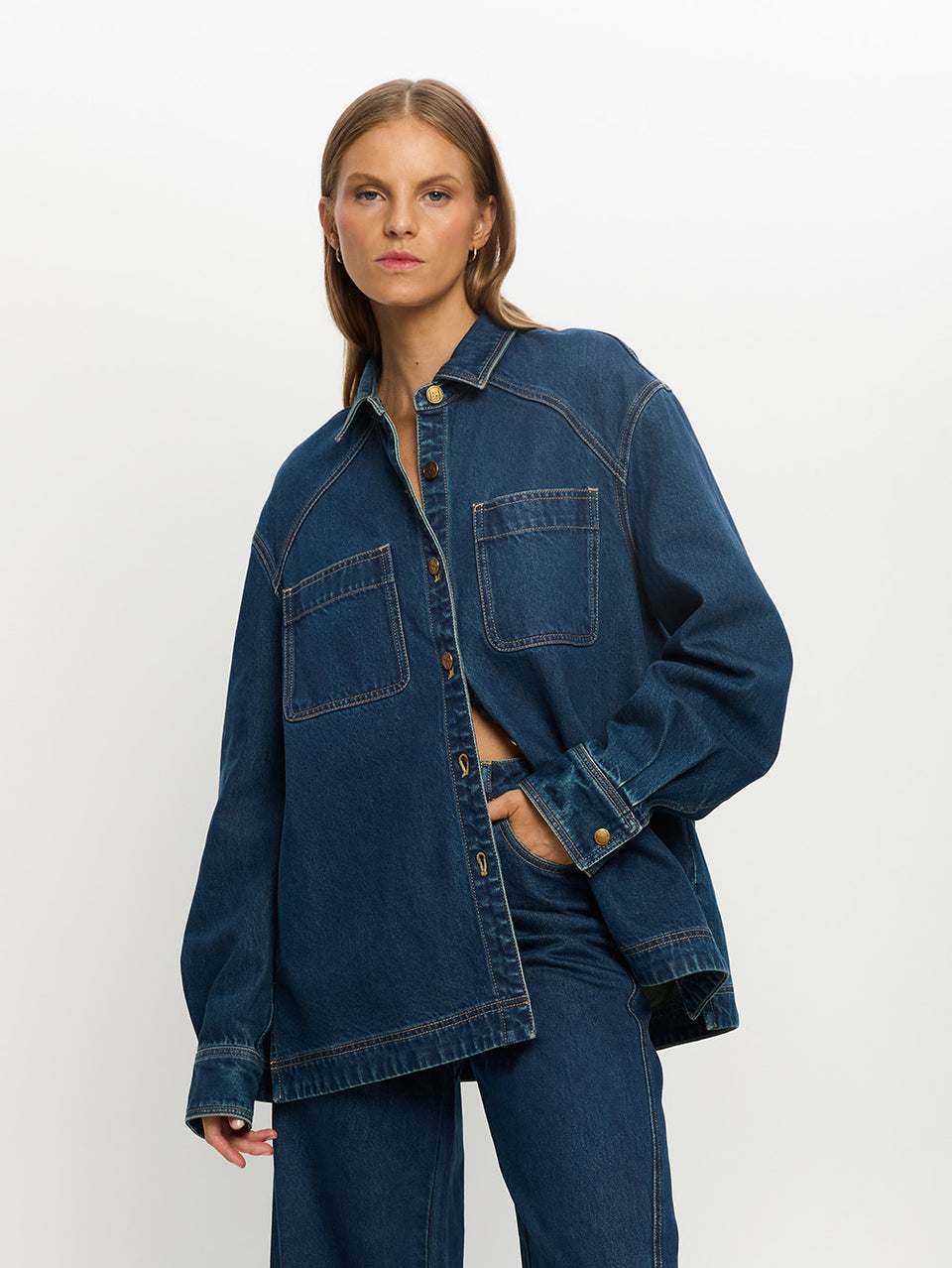 Woman wearing a blue denim jacket and pants on a white background