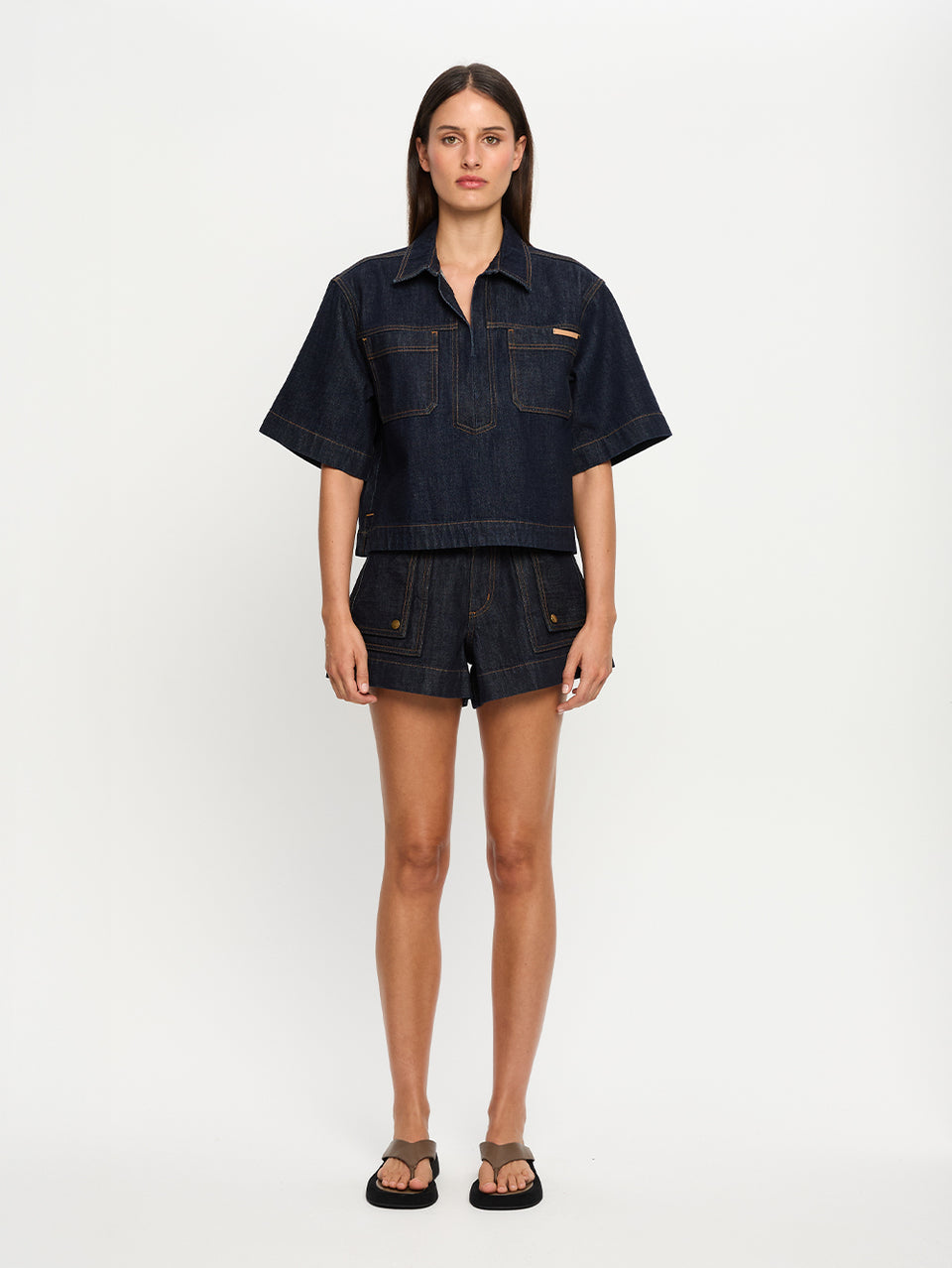 Woman wearing a dark denim outfit on a white background