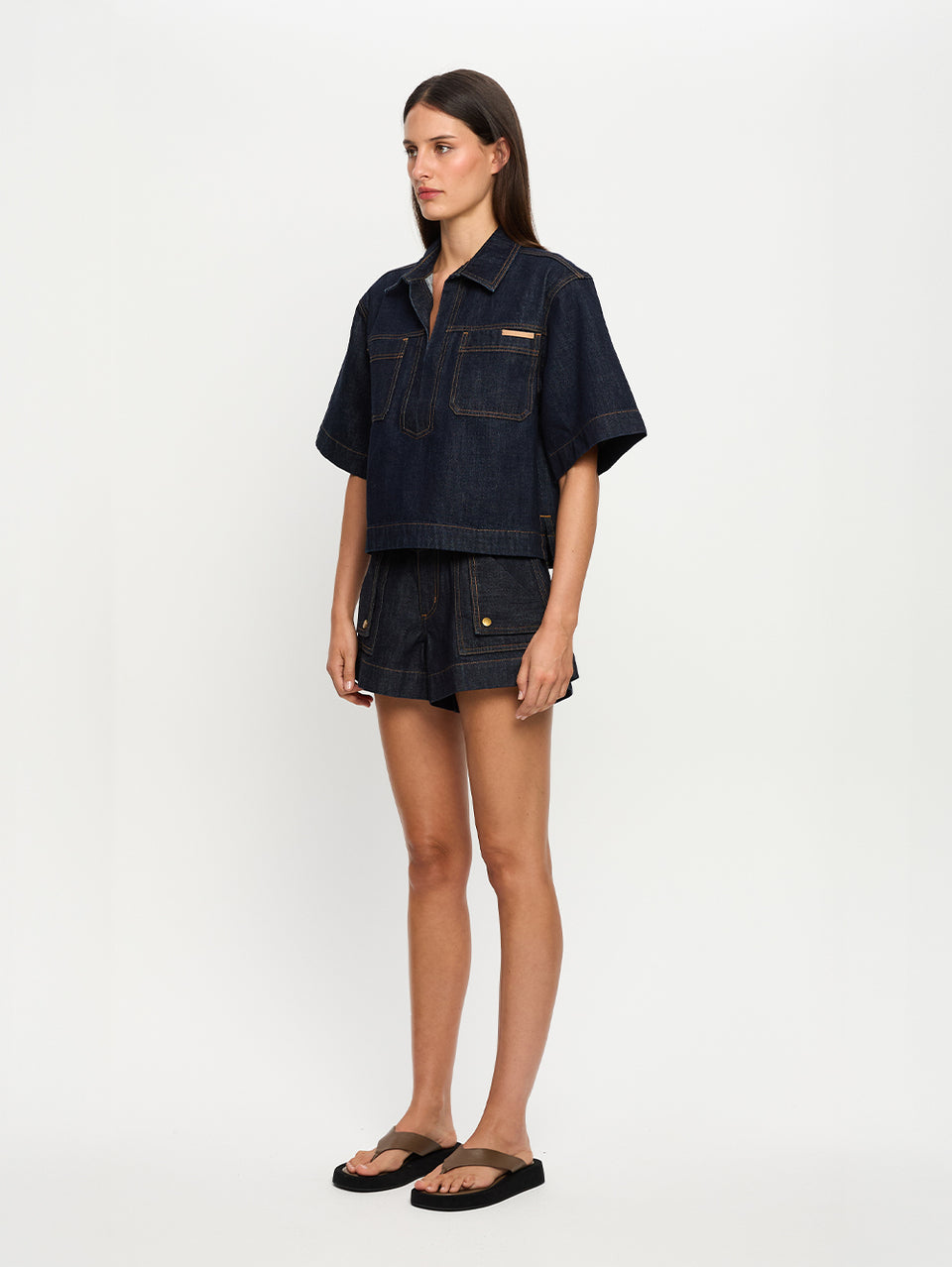 Woman wearing a dark denim shirt and shorts on a white background
