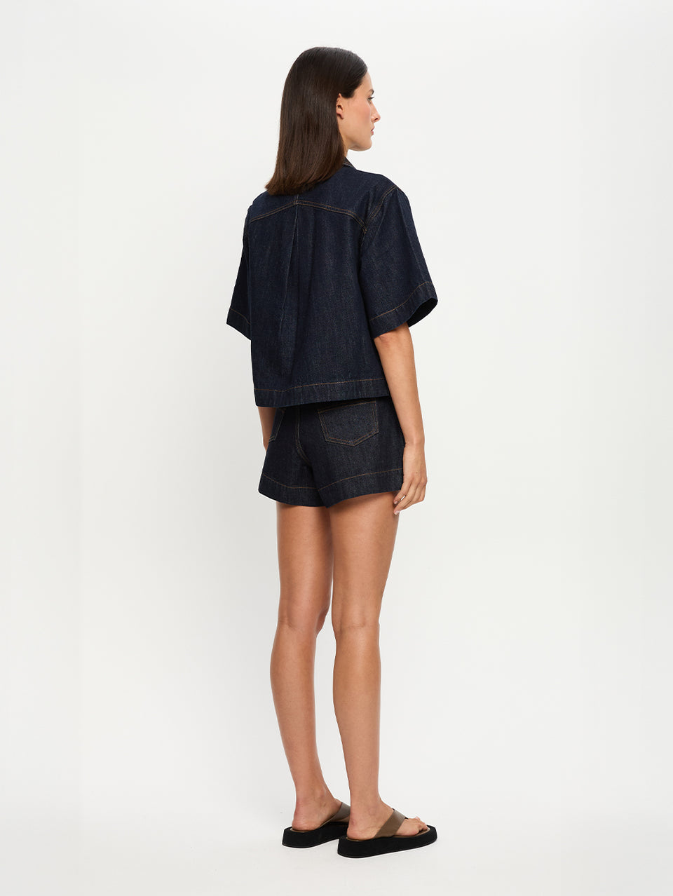 Woman wearing a dark denim outfit on a white background
