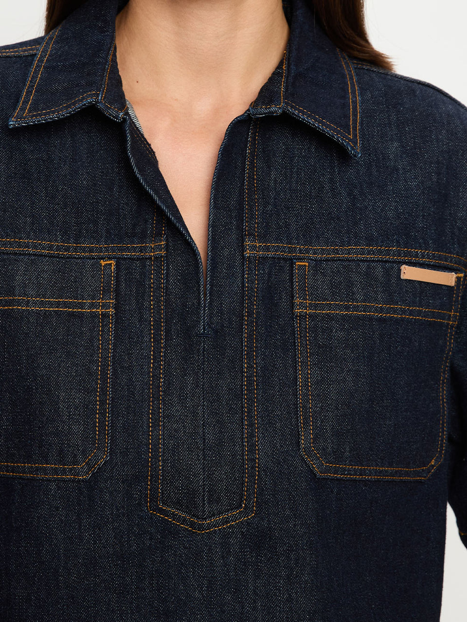 Dark blue denim shirt with collar and front pockets on a plain background