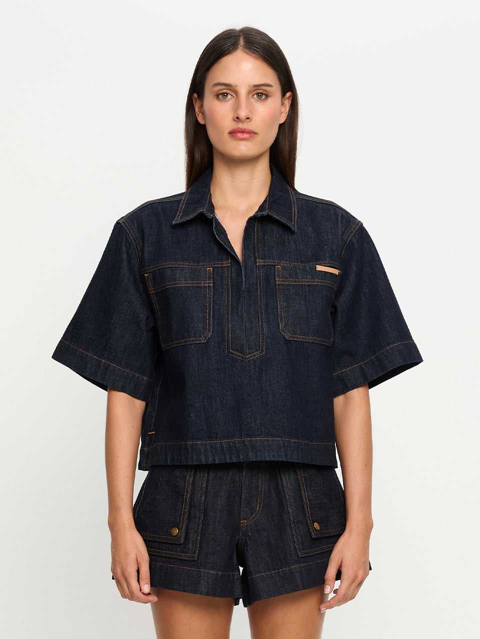 Woman wearing a dark denim outfit on a white background