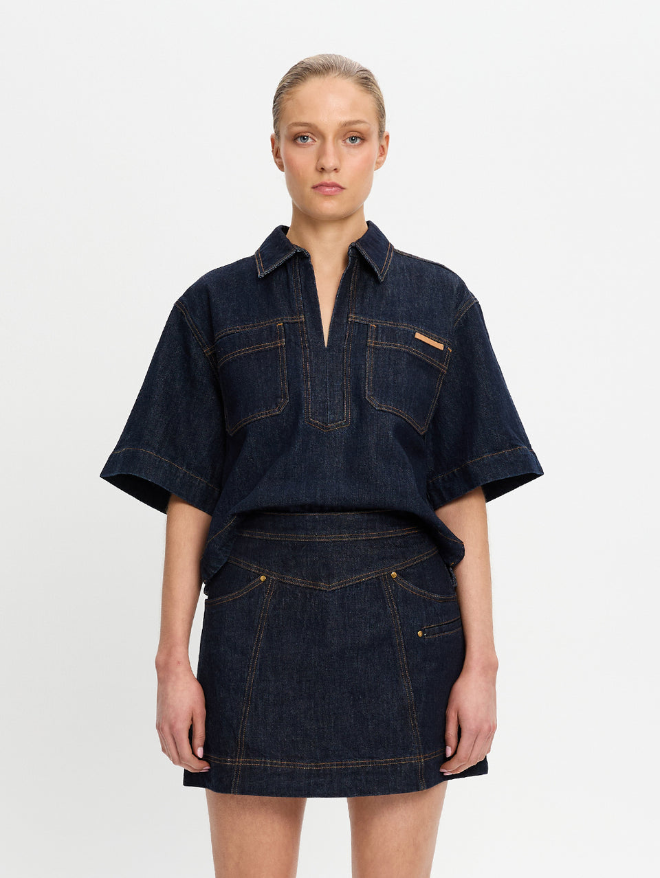 Woman wearing a dark denim outfit on a white background