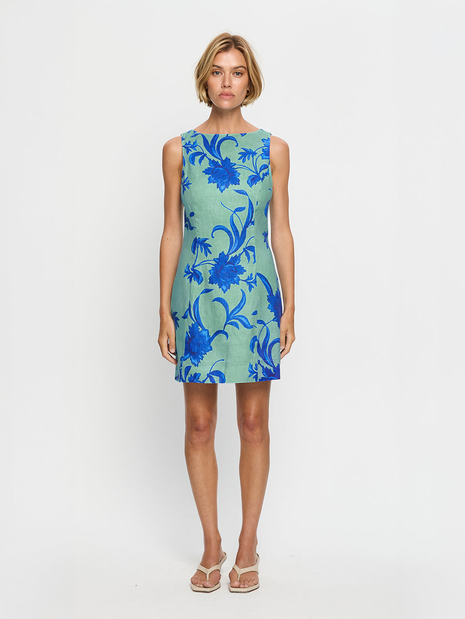 Woman wearing a green dress with blue floral pattern on a white background
