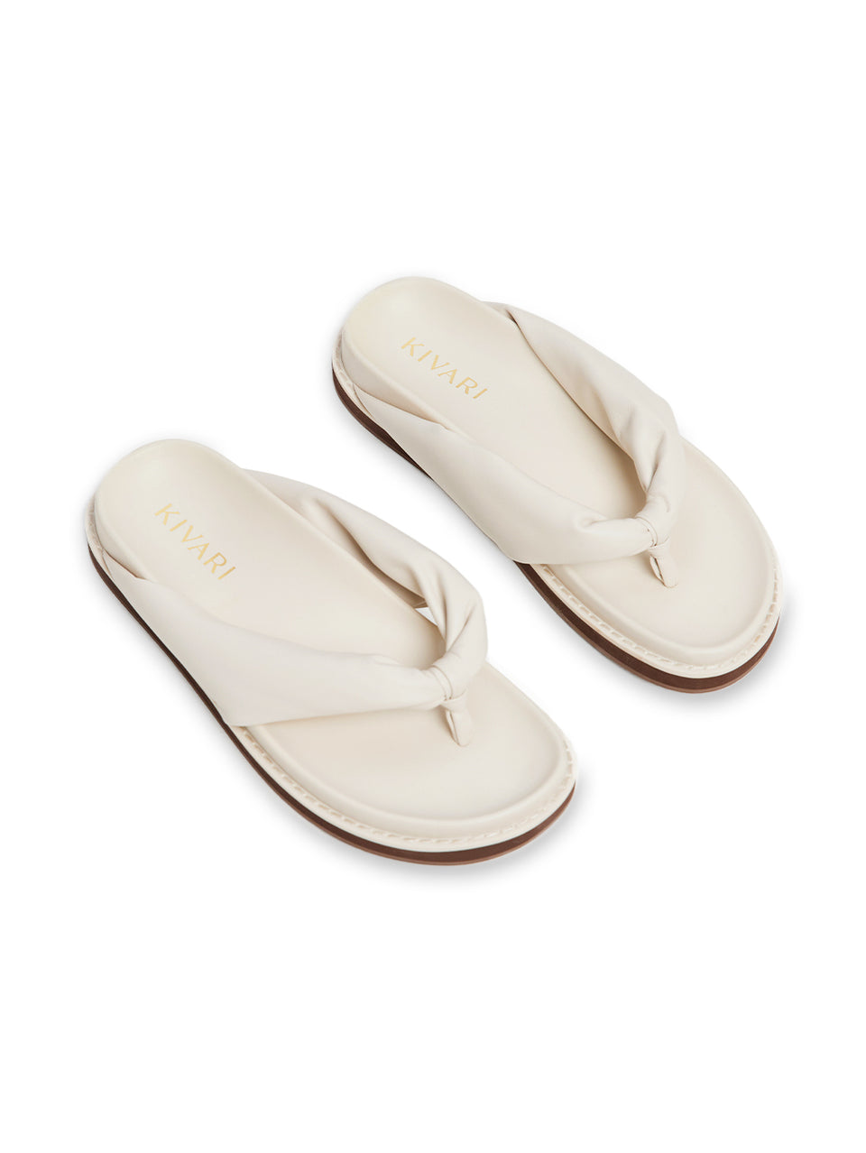 Pair of cream-colored slides with a knot design on a white background