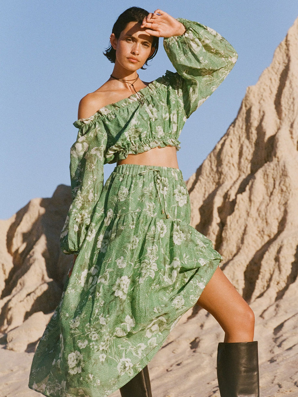 Campaign model wears KIVARI Khalo Midi Skirt: A green floral midi skirt featuring an elasticated drawstring waist with gold bead ends and a gathered tiered skirt.