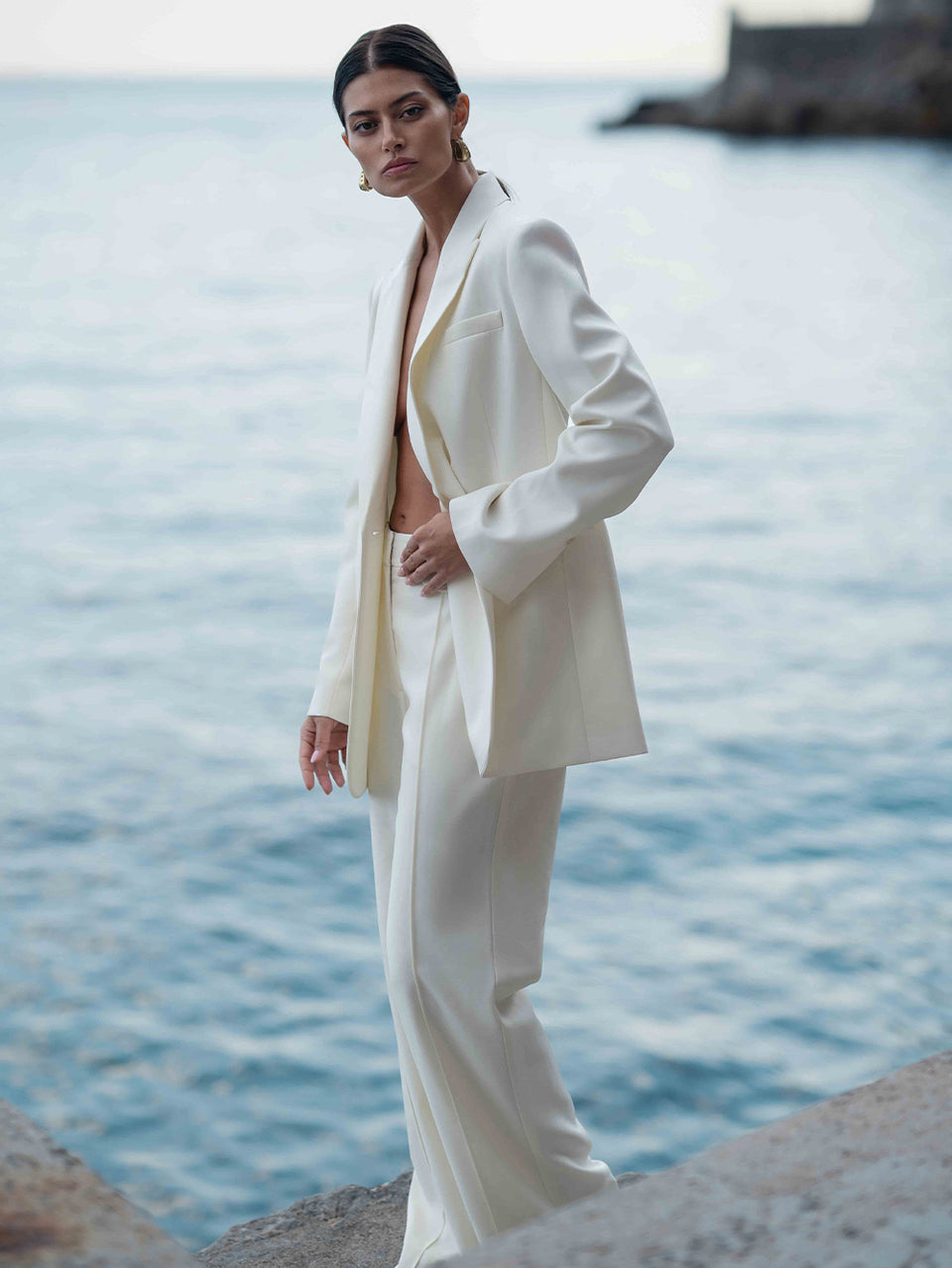 Woman in a white suit standing by the water