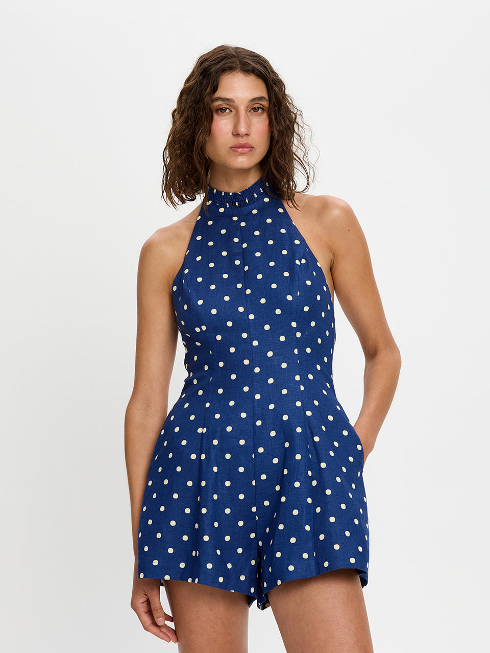 Woman wearing a blue polka dot playsuit on a white background