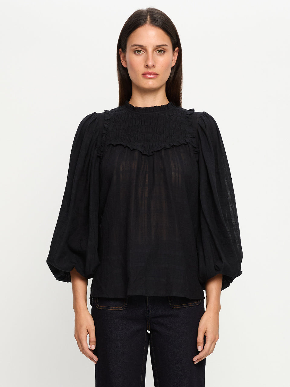 Woman wearing a black blouse with ruffled details on a white background