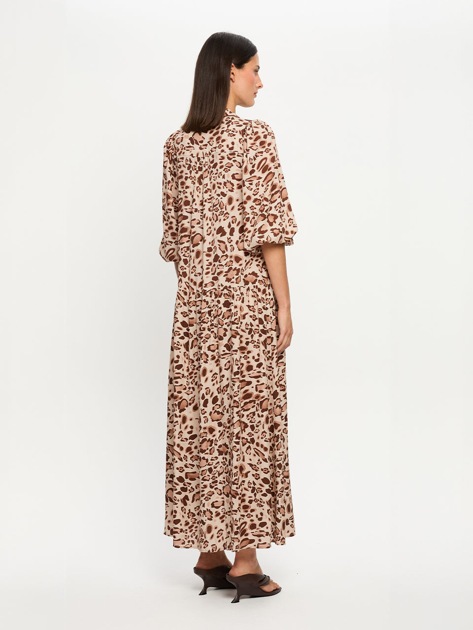 Woman wearing a long, patterned dress on a white background