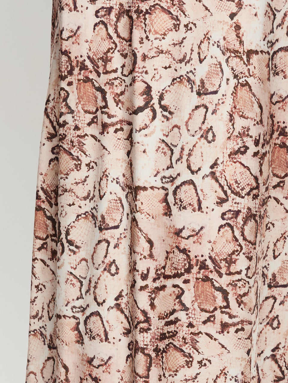 Close-up of a fabric with a snake print pattern on a plain background