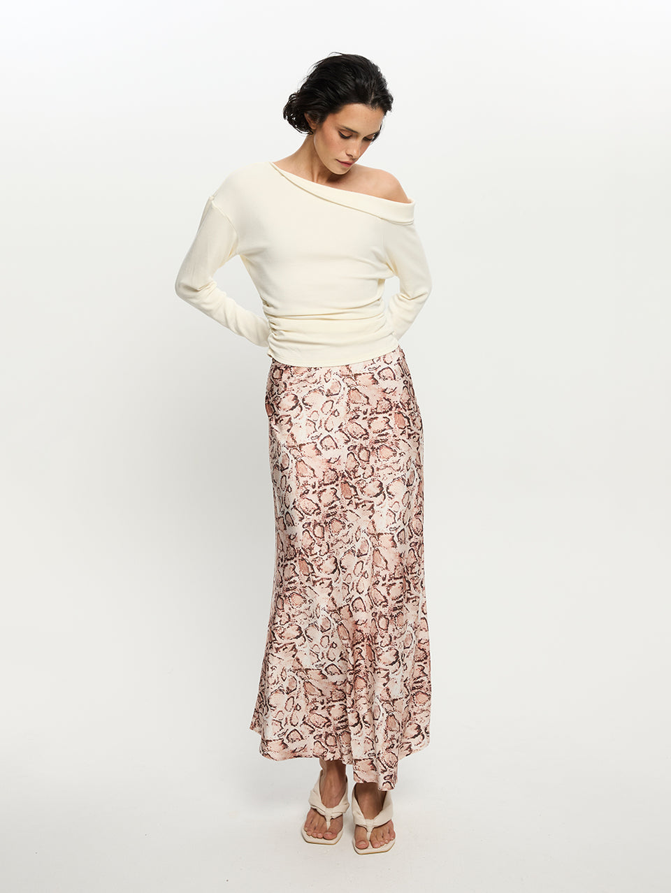 Woman wearing a white off-shoulder top and a patterned skirt on a white background