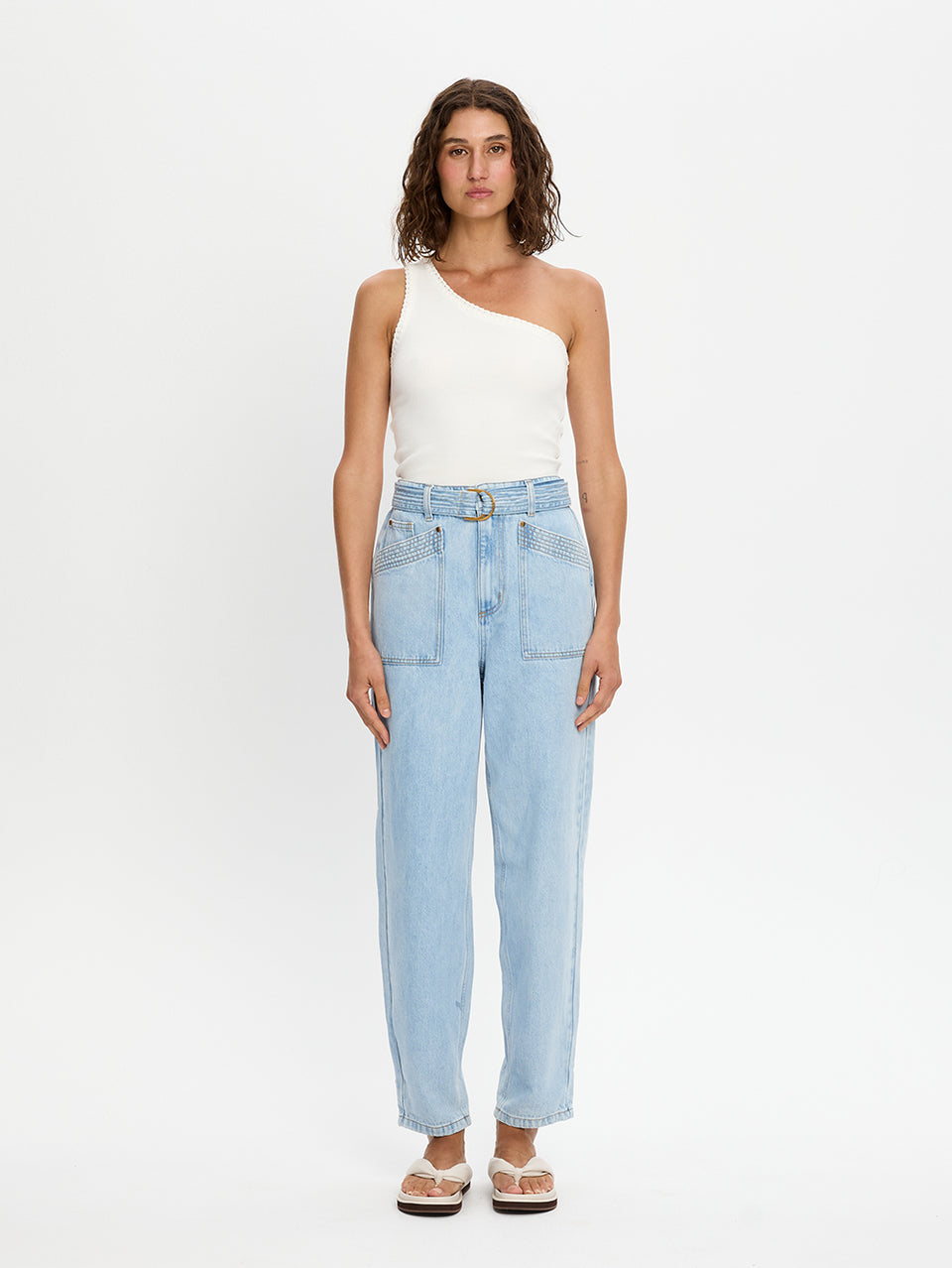 Woman wearing light blue jeans and a white top on a white background