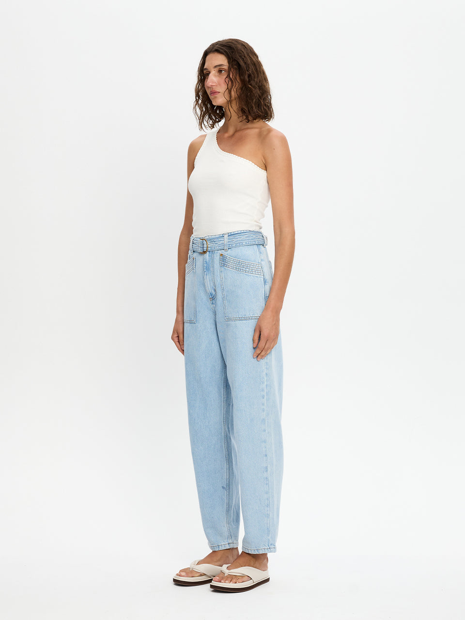 Woman wearing a white top and light blue jeans on a white background