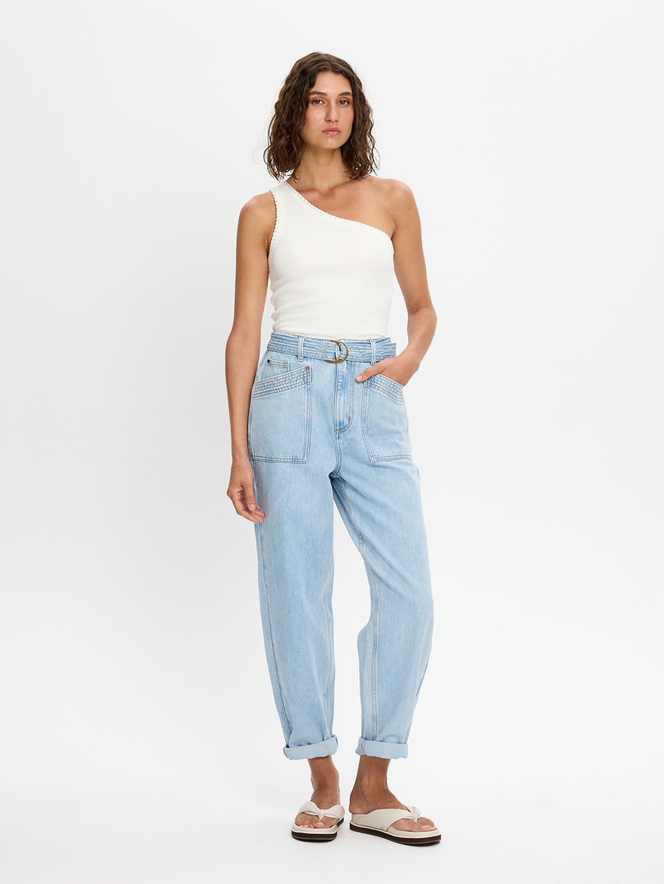 Woman wearing a white top and light blue jeans on a white background