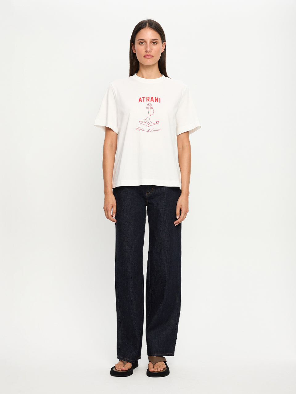 Person wearing a white t-shirt with red text and dark pants on a white background