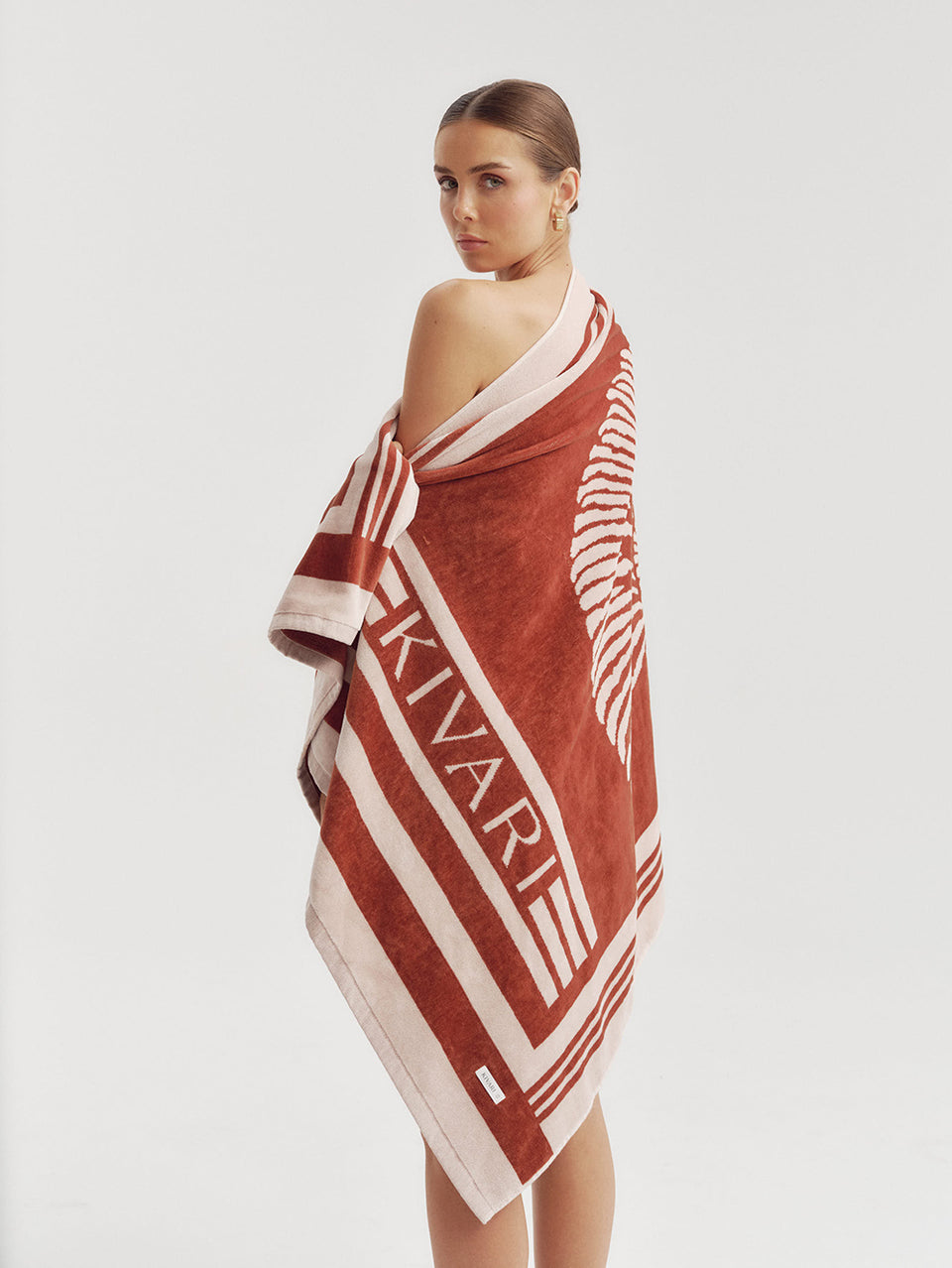 Woman wearing a red and white patterned towel with 'Kivari' branding on a white background