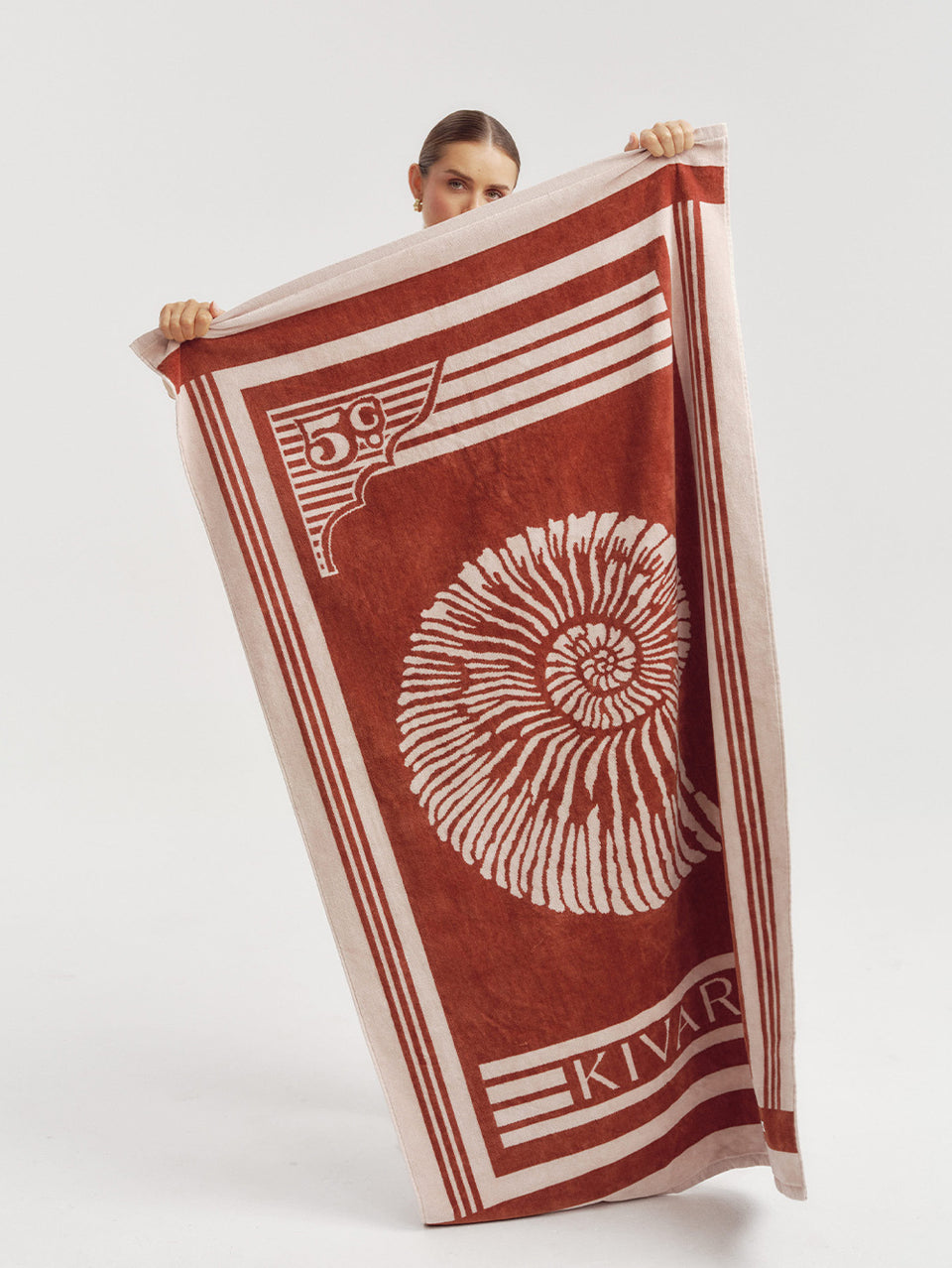 Person holding a red and blush patterned towel with 'Kivar' branding on a white background