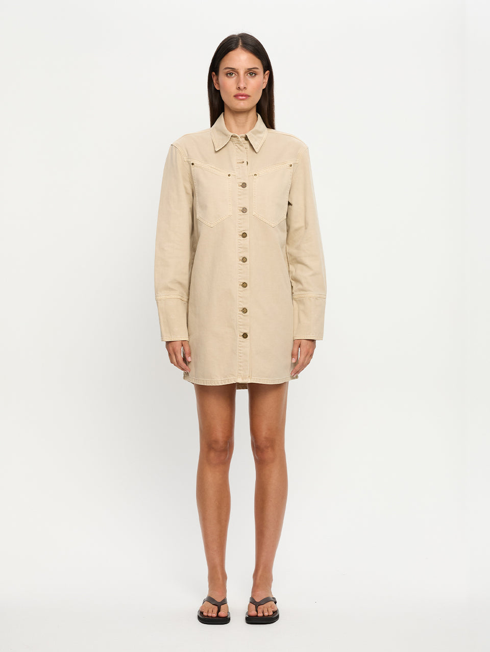 Woman wearing a beige dress with buttons on a white background