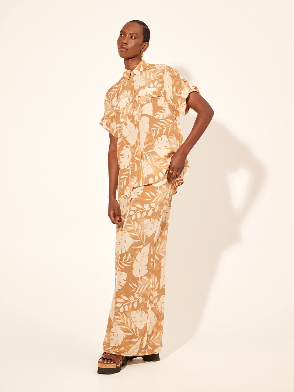 Cove Pant KIVARI | Model wears neutral coloured leaf printed pant side view