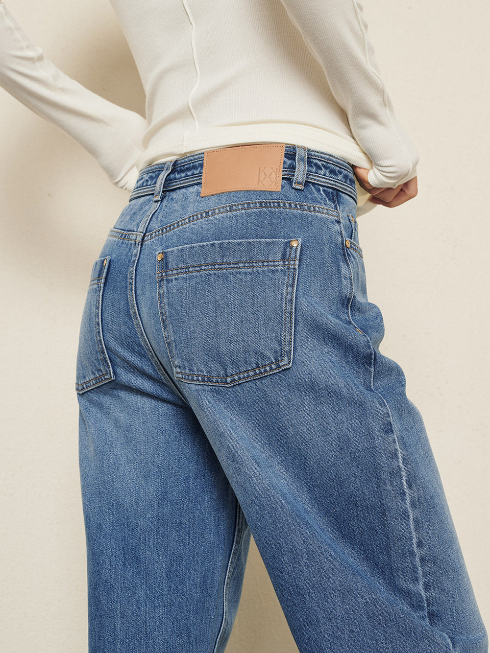 KIVARI Dylan Jeans in Blue – close-up back pocket detail styled with a cream knit sweater