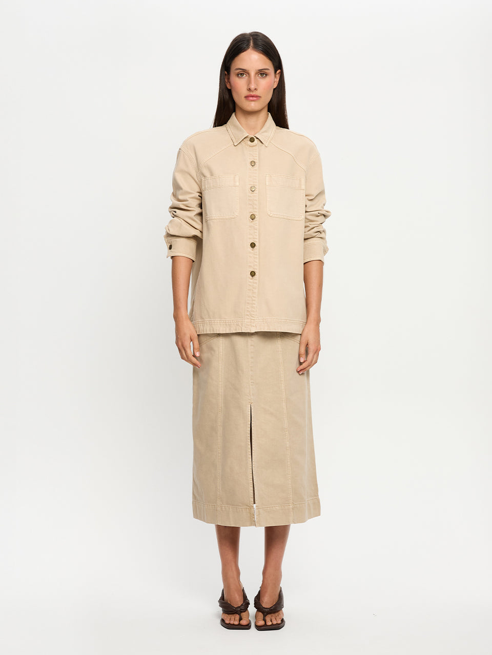 Woman wearing a beige shirt and skirt on a white background
