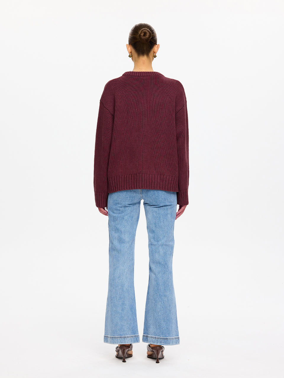 KIVARI Odette Crew Neck Jumper in Plum - back view of model wearing dark plum ribbed knit jumper with light blue flared jeans