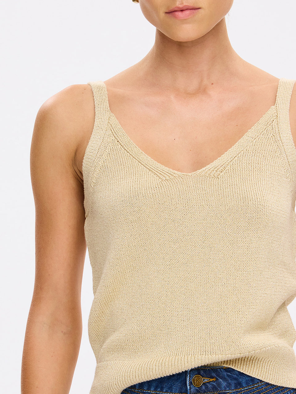 Beige knitted tank top worn by a person on a plain background