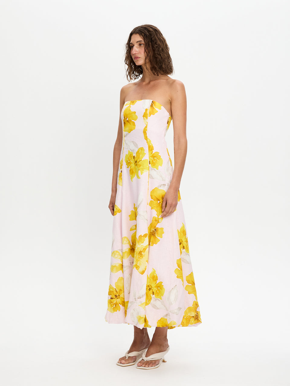 Woman wearing a strapless dress with yellow floral pattern on a white background