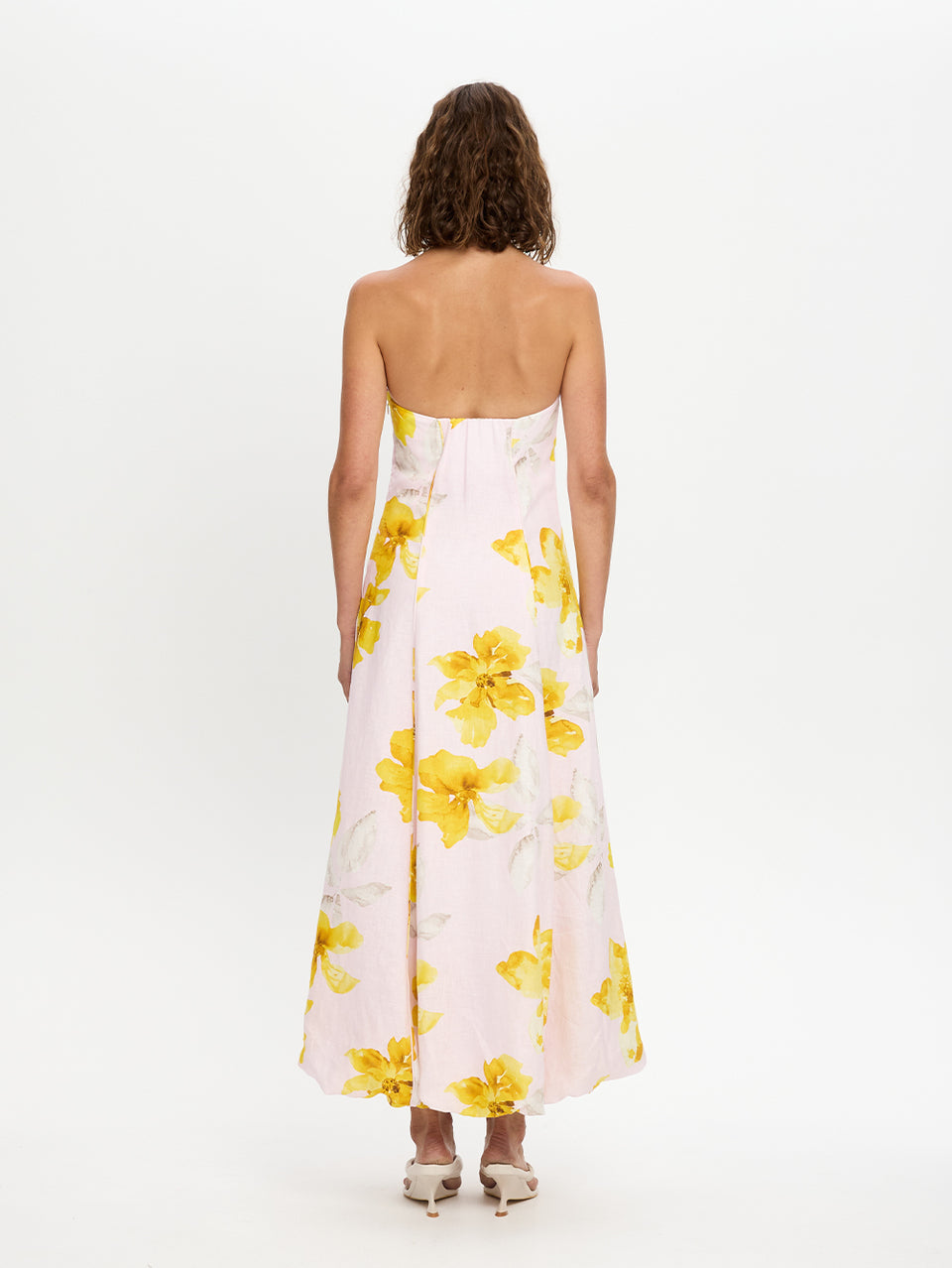 Woman wearing a strapless dress with yellow floral pattern on a white background