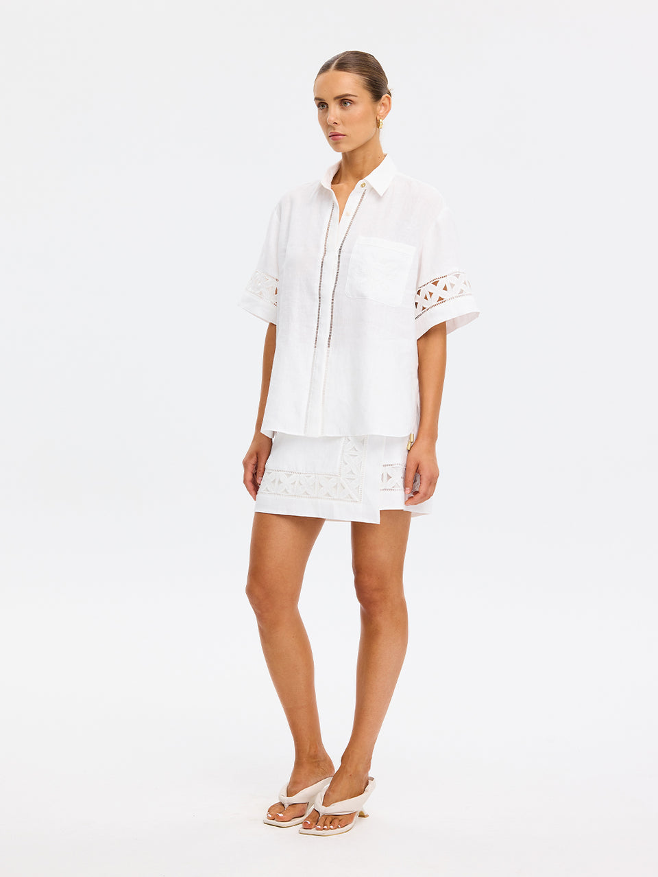 Woman wearing a white dress with lace details on a white background