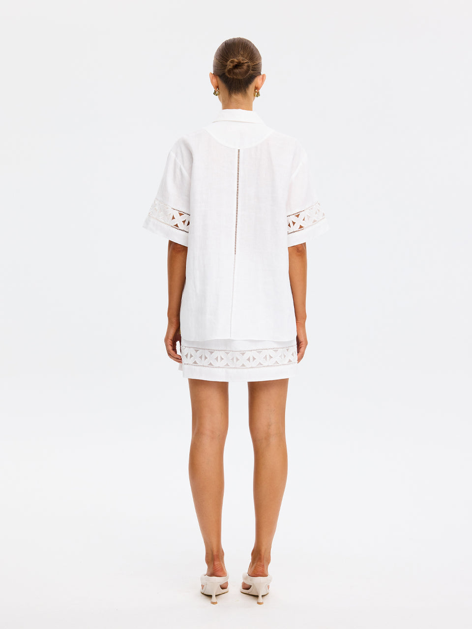 Woman wearing a white dress with lace details on a white background