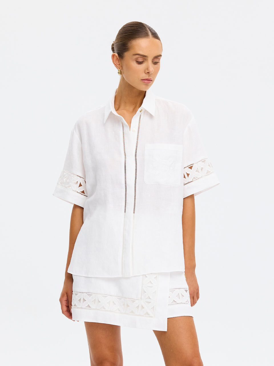 Woman wearing a white outfit with lace details on a white background