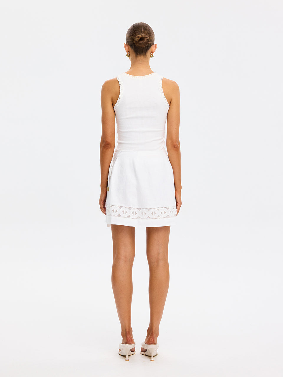 Woman wearing a white dress with lace details on a white background