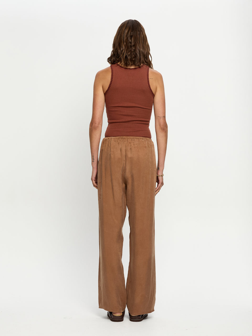 Woman wearing a brown tank top and wide-leg pants on a white background