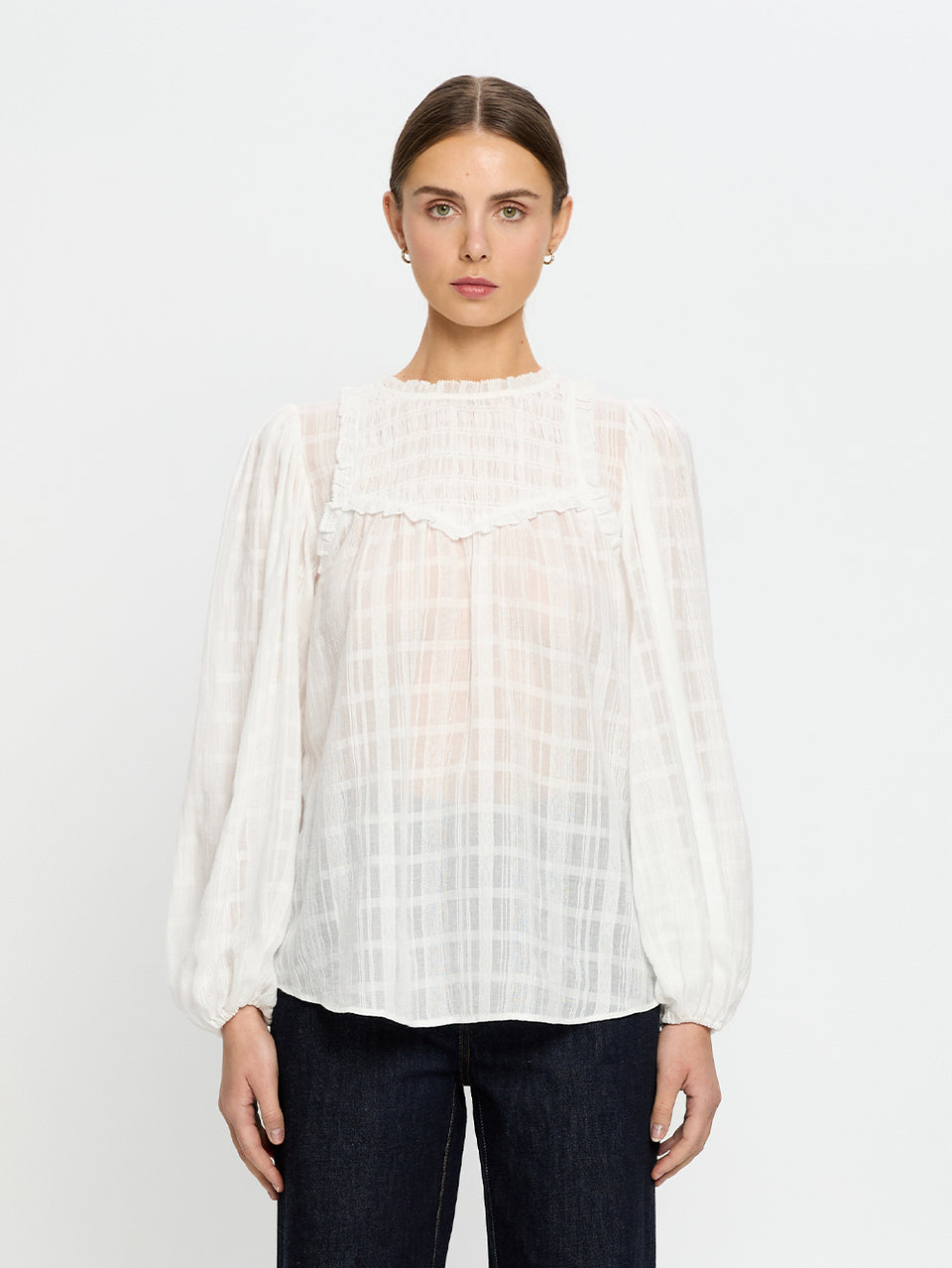 Woman wearing a white blouse with long sleeves on a plain background