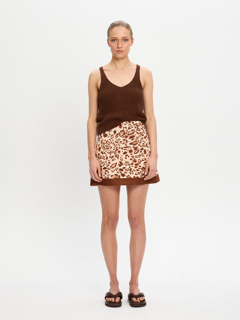 Woman wearing a brown tank top and leopard print skirt on a white background