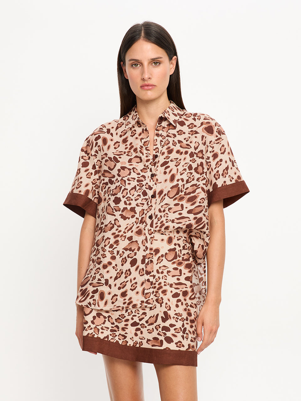 Woman wearing a leopard print top and skirt with brown trim on a white background