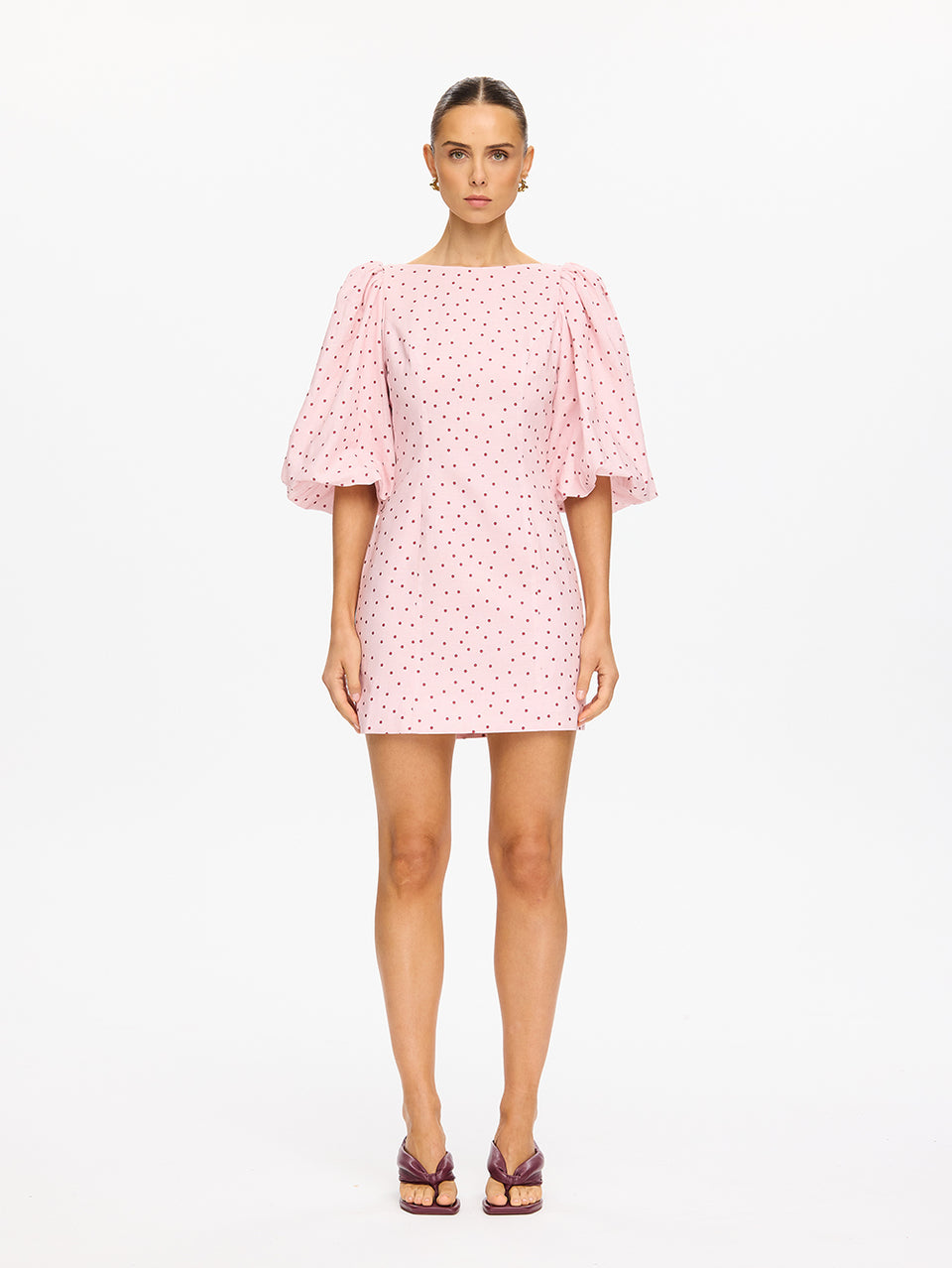 Woman wearing a pink polka dot dress on a white background