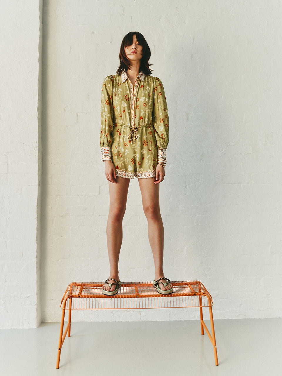 Model Wearing KIVARI Salome Playsuit, standing on chair