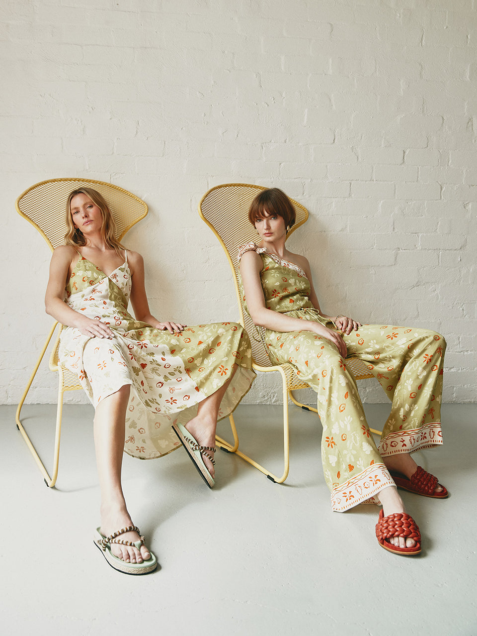 Models wearing KIVARI Salome Slip Dress, Top & Pants, sitting in chairs
