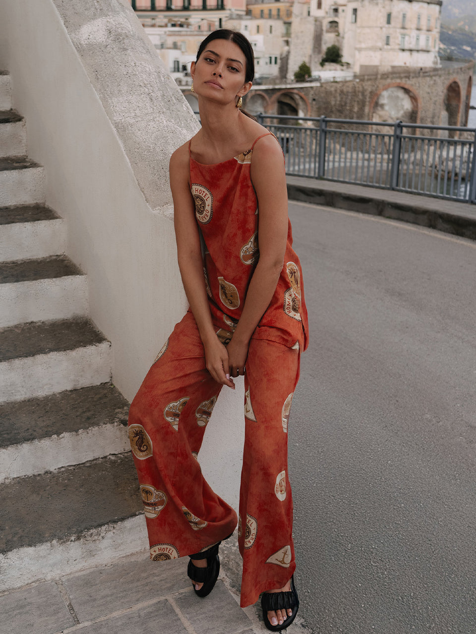 Woman in a red patterned outfit standing on stone steps with a scenic background